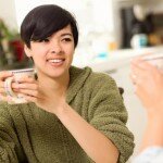 Multi-ethnic Young Attractive Woman Socializing with Friend in Her Kitchen.