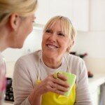 Mother and daughter talking, drinking coffee in kitchen