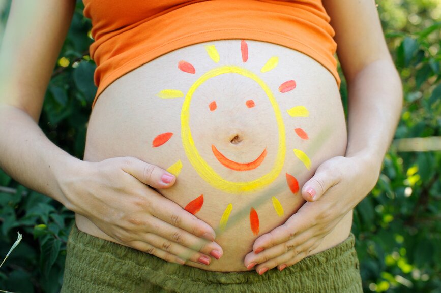 Pregnant woman abdomen with drawing sun.